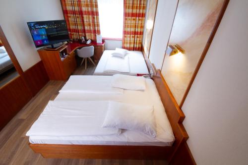 a room with two beds and a desk with a television at Vienna Sporthotel in Vienna