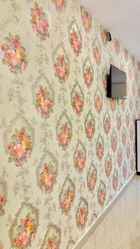 a wall with a floral wallpaper with a tv on it at The First Floor I Top Rated Boutique Homestay I Near Lekhraj Metro Lucknow in Lucknow