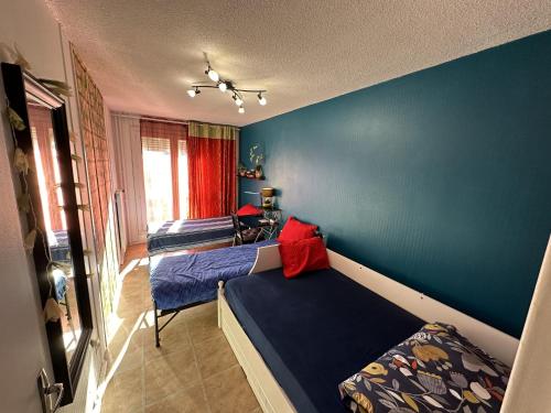 une chambre avec deux lits et un mur bleu dans l'établissement Meublé Les Dômes du Parc 6ème, à Clermont-Ferrand