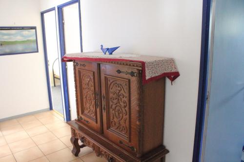 une armoire en bois avec un tissu de table rouge au-dessus dans l'établissement Villa du Bac, à Chambon-sur-Lac