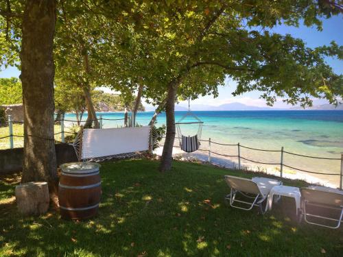 a picnic table and chairs under a tree next to the beach at Ferienhaus Simos In Paleokastro in Edipsos