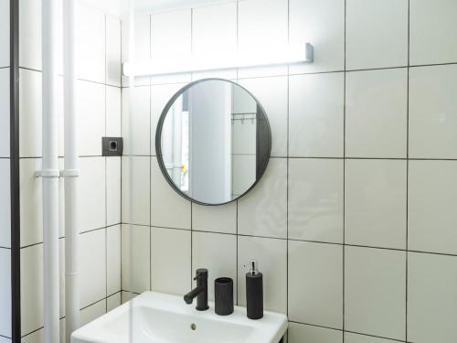 La salle de bains est pourvue de carrelage blanc, d'un lavabo et d'un miroir. dans l'établissement Aura - Old Town, à Bucarest