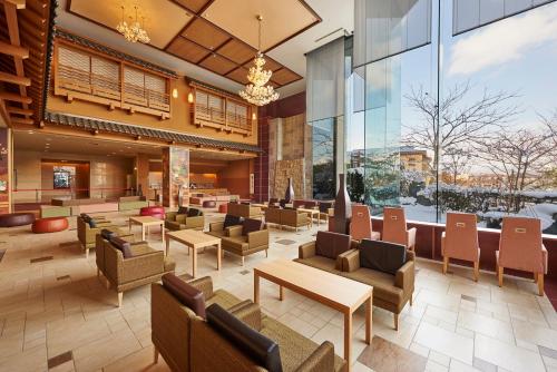 a lobby with chairs and tables and windows at Heiseikan Kaiyotei in Hakodate