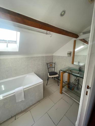 a bathroom with a tub and a sink and a chair at joli T3 au coeur de lourdes in Lourdes