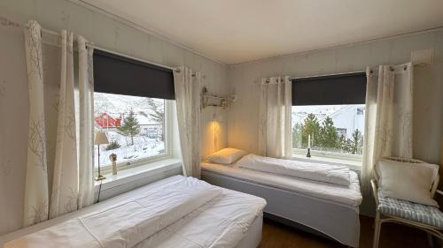 two beds in a room with two large windows at Nonstinden View Lofoten in Ballstad