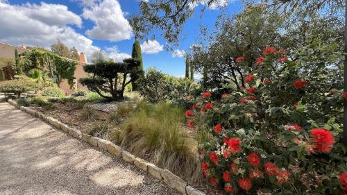 un jardin avec des fleurs rouges dans une cour dans l'établissement Le Mas de La Calabro, à La Valette-du-Var
