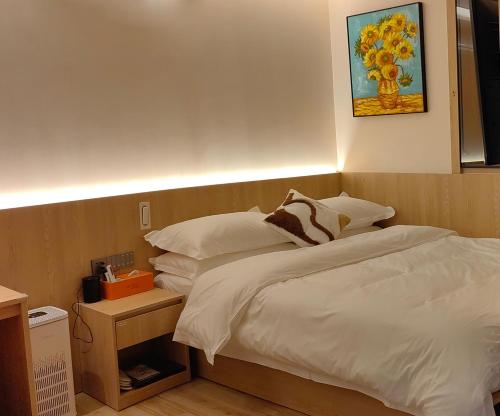a bed with white sheets and pillows in a room at Andy International Hotel Shenzhen University Nanshan Metro Station Branch in Shenzhen