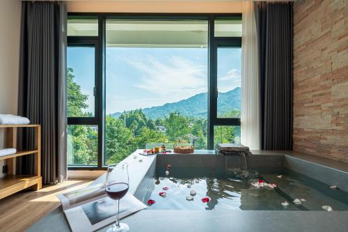 a room with a bath tub with a glass of wine at Z HOTEL- Qingchengshan in Dujiangyan
