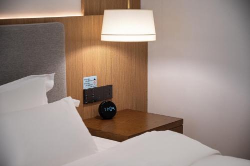 a bedroom with a bed and a clock on a night stand at Z HOTEL- Qingchengshan in Dujiangyan