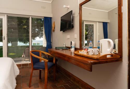 a room with a vanity with a mirror and a bed at Sunbird Chintheche in Nkhata Bay