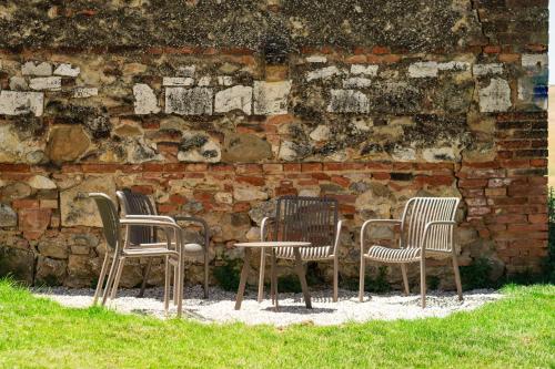 three chairs and a table in front of a brick wall at Borgo Belsedere - Apartments at a historic estate in Tuscany in Trequanda