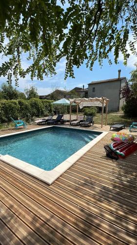 une piscine avec des chaises et une terrasse en bois dans l'établissement Le Mas de L'Arceau - Mas avec piscine en Sud Ardèche, à Grospierres