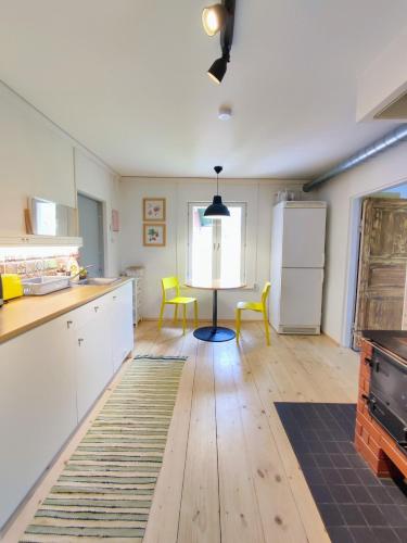 a kitchen with white cabinets and yellow chairs in it at Serene Holiday Home next to Nature Reserve in Kärde