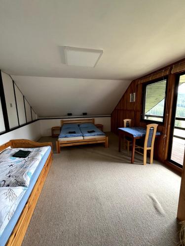 a room with two beds and a table in it at Chata s výhledem do údolí Frymburk, Náhlov in Frymburk