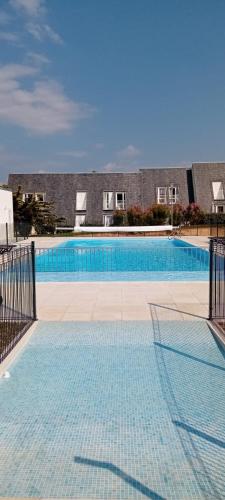 une grande piscine bleue avec un bâtiment en arrière-plan dans l'établissement Duplex bord de mer tout confort avec terrasse et parking, plage à pied par Groom, à Guidel