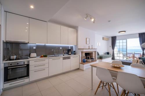 a kitchen with white cabinets and a table with chairs at Luxuriöses Apartment Mit Einem Schlafzimmer Direkt Am Wasser, Meerblick in Kivérion