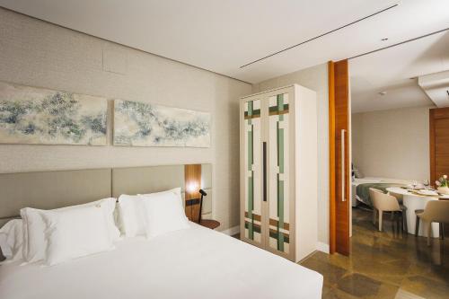 a bedroom with a white bed and a dining room at Corral del Carbón GG Luxury Hotel Boutique in Granada