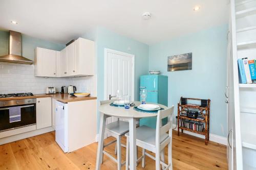 a kitchen with a white table and a blue refrigerator at Host & Stay - Blue Bolthole on Vicarage Lane in Rottingdean