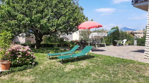 two green chairs and a red umbrella in a yard at 02 Virgilio Zanetti in San Zeno di Montagna