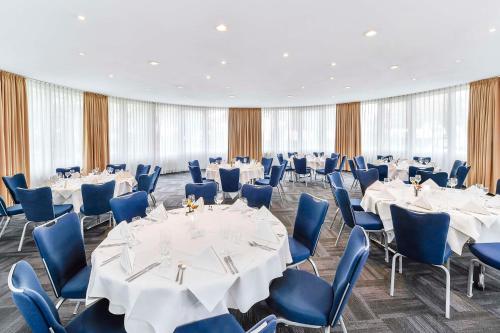 a banquet hall with white tables and blue chairs at NH Weinheim in Weinheim