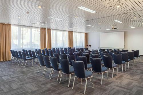 a conference room with chairs and a white screen at NH Weinheim in Weinheim