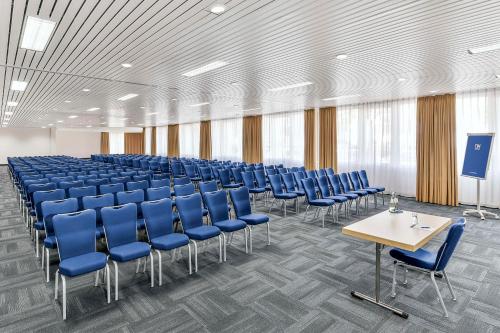 a conference room with blue chairs and a table at NH Weinheim in Weinheim