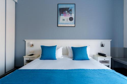 a blue bedroom with a white bed with blue pillows at Hôtel Marso in Amnéville