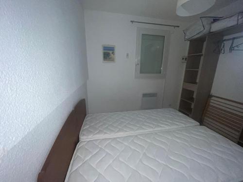 a small bedroom with a white bed in it at appartement dans un residence avec piscine - 3254 in Hourtin