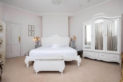 a white bedroom with a white bed and a mirror at Host & Stay - St Aubyns Coastal Retreat in Brighton & Hove