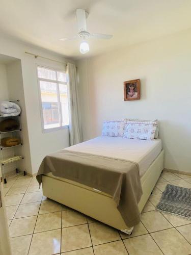 a bedroom with a bed in a room with a window at Bela vista a beira mar in Marataizes