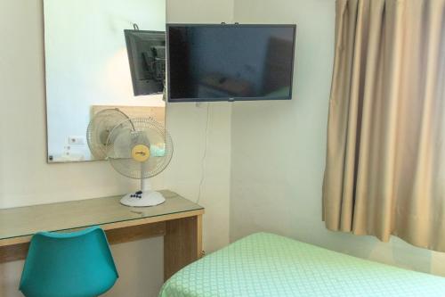 a room with a fan and a tv and a chair at Hostal Magec in Puerto del Carmen