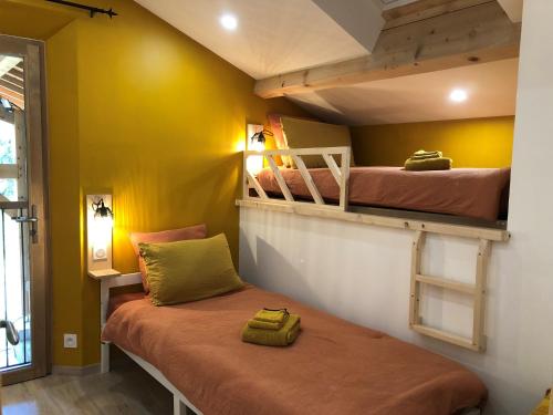 2 Etagenbetten in einem Zimmer mit gelben Wänden in der Unterkunft L'Hospitalier in Saint-Antoine