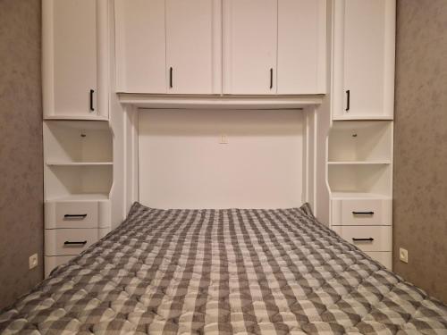 einen Schrank mit weißen Schränken und einem Bett in der Unterkunft Premium Holidays - Studio Vriedom at the sea in Oostduinkerke