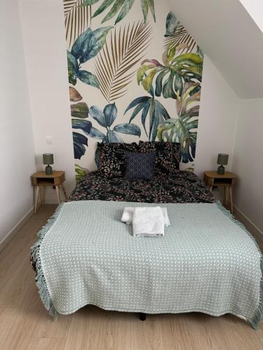 une chambre avec un grand lit et un papier peint tropical dans l'établissement Maison Kervignac, à Kervignac