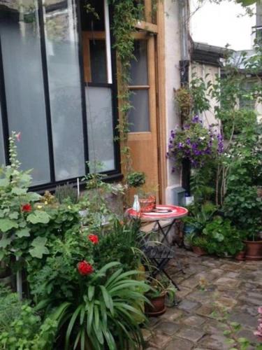 un jardin avec des fleurs et des plantes devant un bâtiment dans l'établissement L'Atelier d'artiste, à Paris