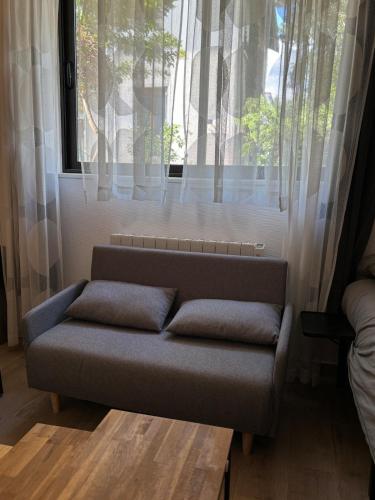 un canapé installé devant une fenêtre dans l'établissement Suite Lyon Coeur Monplaisir, à Lyon