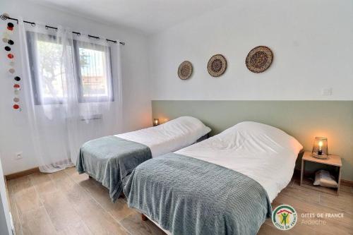 une chambre avec deux lits et une fenêtre dans l'établissement Le Bonelli, au coeur de l'Ardèche, à Saint-Remèze