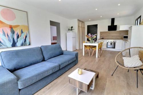 un salon avec un canapé bleu et une cuisine dans l'établissement Le Bonelli, au coeur de l'Ardèche, à Saint-Remèze