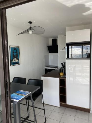 une cuisine avec une table et des chaises dans une pièce dans l'établissement Appartement Vue mer Le Sunset, au Cap d'Agde