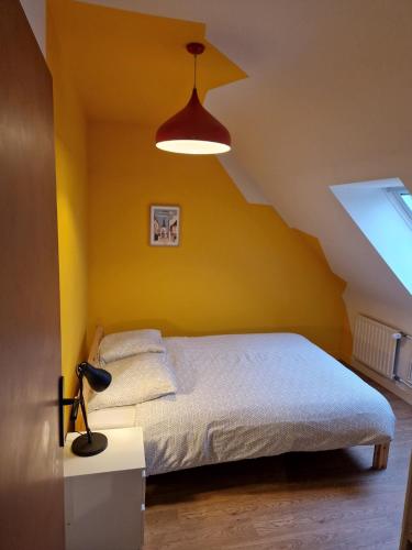 une chambre avec un lit avec un mur jaune dans l'établissement Maison LANVALLAY, à Lanvallay
