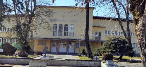 Un edificio amarillo con un hombre parado frente a él. en Апартамент Калоян, en Banya