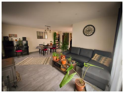 un salon avec un canapé et une horloge au mur dans l'établissement Chambre dans grande maison paisible, à Paulhan