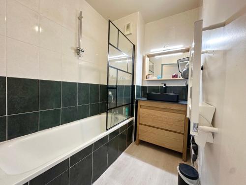 une salle de bain avec une baignoire, un lavabo et un miroir dans l'établissement Les Gemmeurs - T2 proche du lac, à Aureilhan