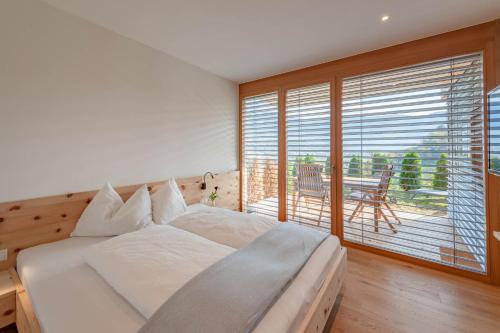 a bedroom with a white bed and a large window at Moosbichlerhof in Marlengo