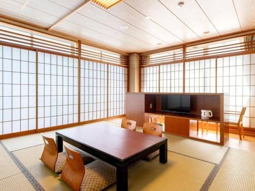 a large room with a table and a tv at Kurhouse Shirahama in Shirahama