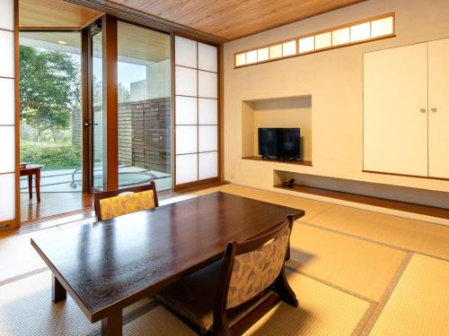 a dining room with a table and a tv at Kurhouse Shirahama in Shirahama