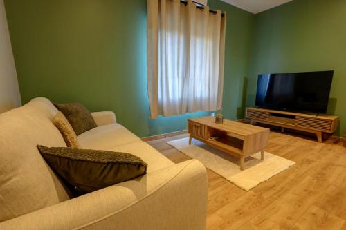 a living room with a couch and a flat screen tv at Havre de paix près de Pérouges, charme et confort in Faramans