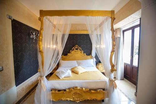 a bedroom with a gold canopy bed with curtains at Hotel Il Principe in Milazzo
