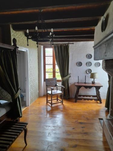 une pièce avec une chaise, une table et une fenêtre dans l'établissement Lo Vielh Ostal, à Saint-Paul-Lizonne