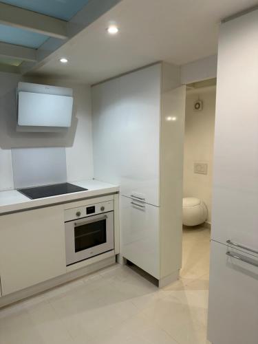Il comprend une cuisine blanche équipée d'une cuisinière et d'un réfrigérateur. dans l'établissement LOFT vieille ville Cannes proximité plage et palais des festivals, à Cannes